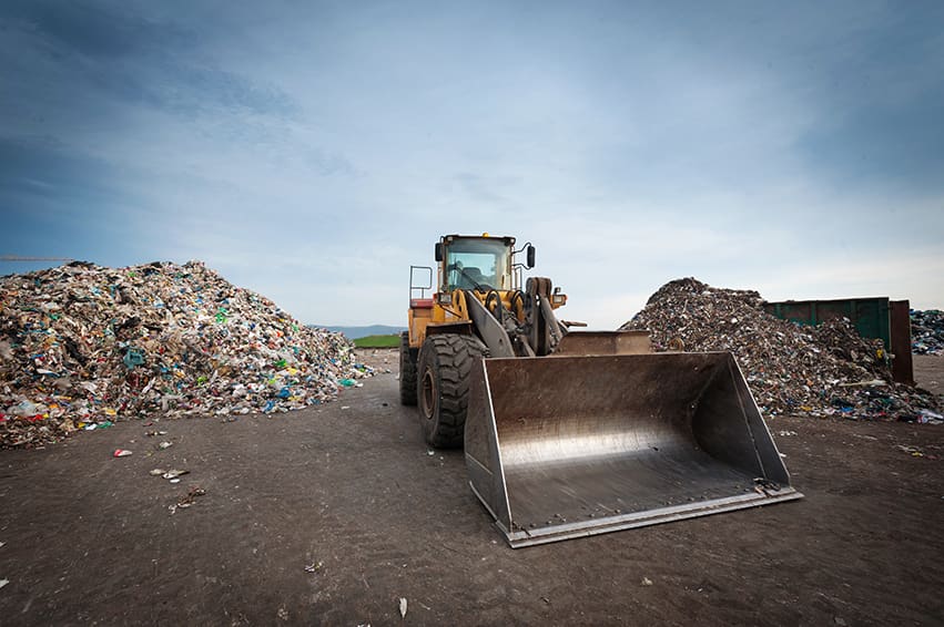 Bulldozer in front of pile of waste at city recycling landfill