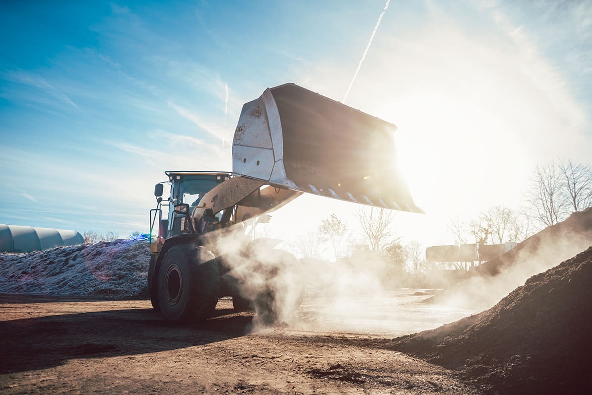 Bulldozer putting biomass on pile for composting in industrial facility