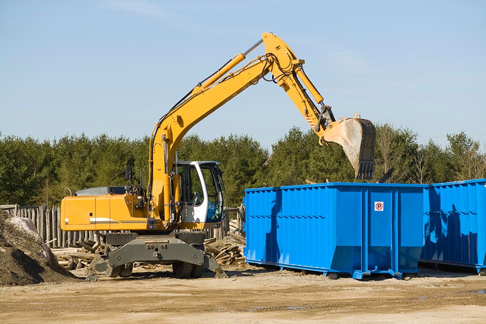 yellow demolition bulldozer beside a dumpster