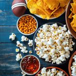 Top view of snacks for watching a football game with copy space over wooden table background. Super bowl concept - AI Generated